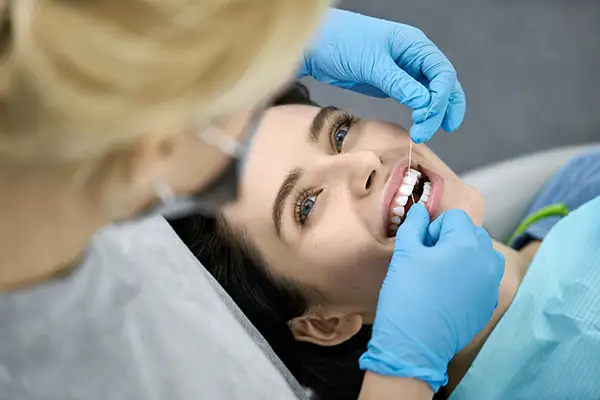 A woman receiving a flossing during a dental visit