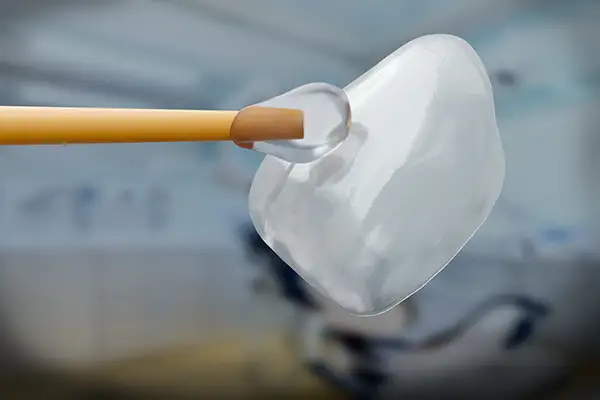 A close-up of a dental veneer being delicately touched with a tool