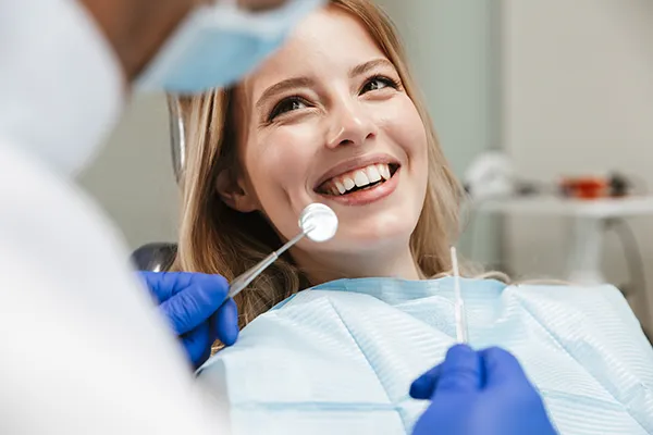 A female patient happily waiting in a dental chair for her dentist to begin her routine exam